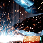 A man with a face shield grinding, representing the need for our dust collection systems.