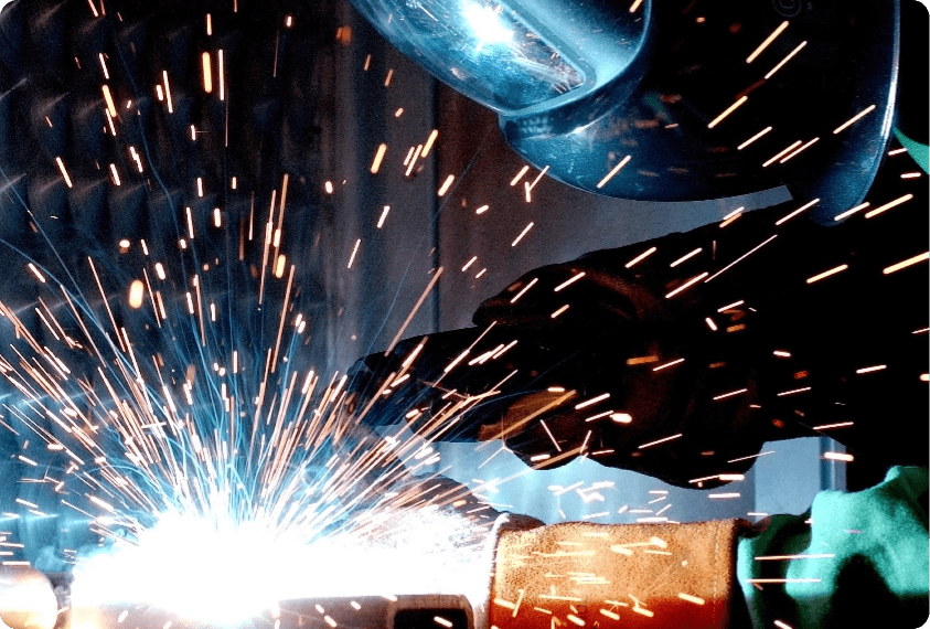 A man with a face shield grinding, representing the need for our dust collection systems.