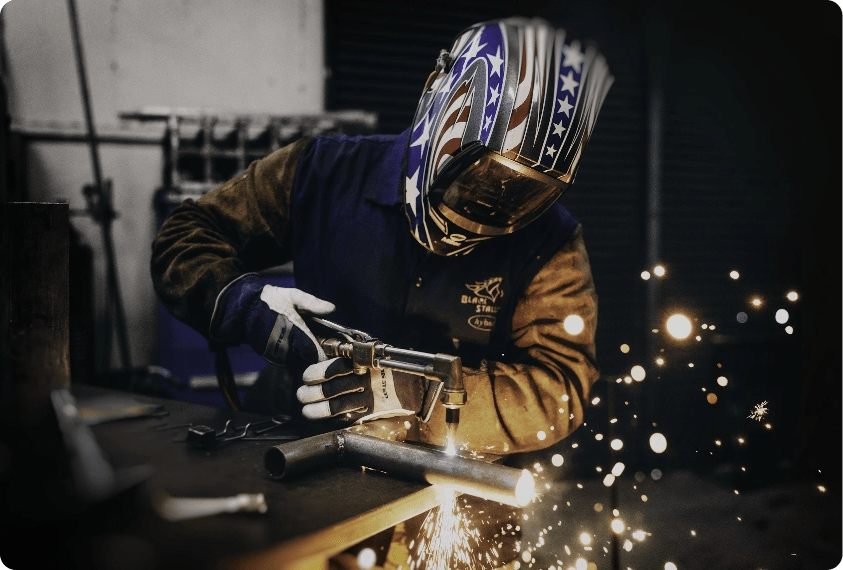 A man with a face shield laser and plasma cutting, representing the need for our dust collection systems.