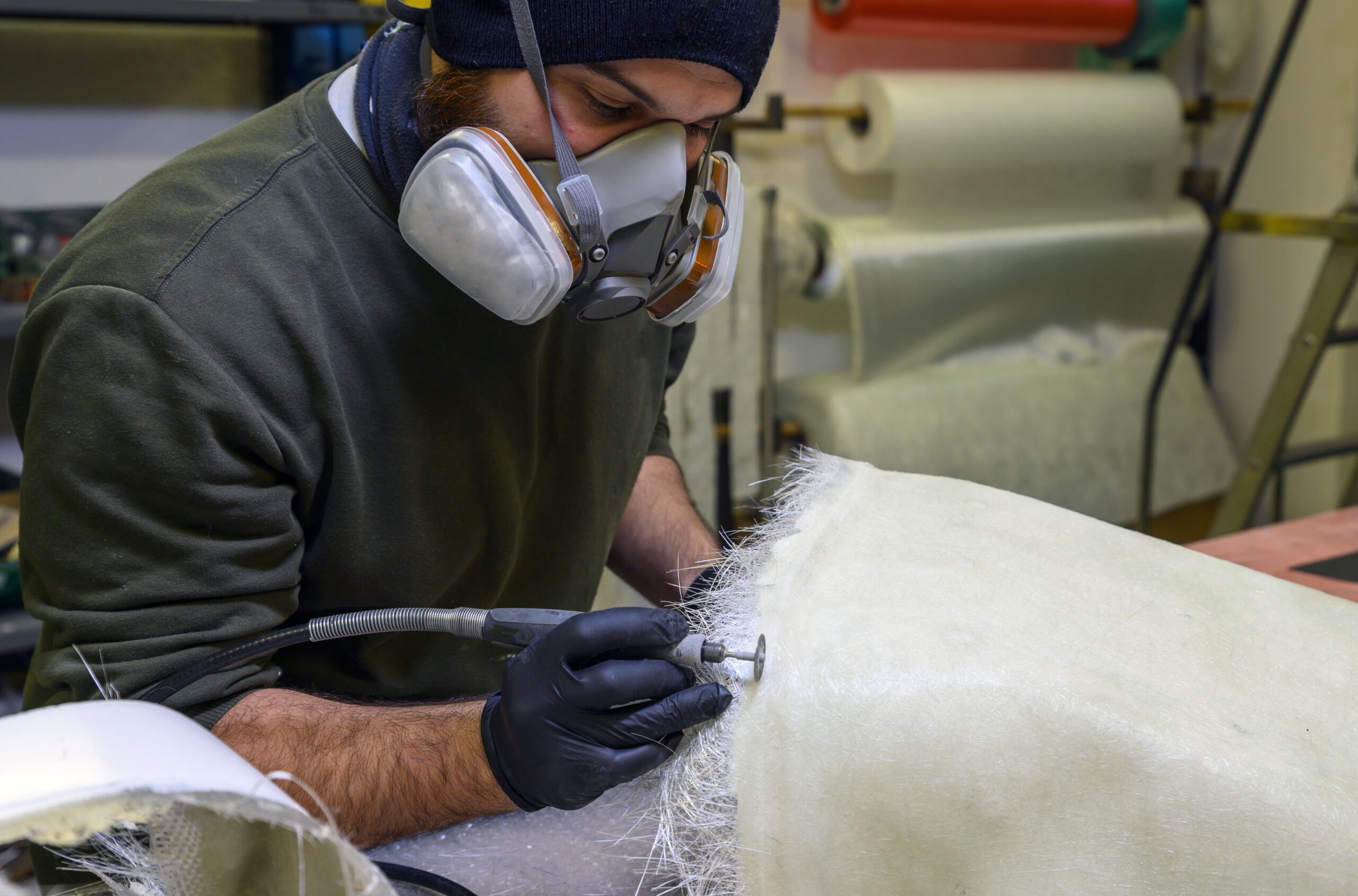 A man with a protective mask doing composite work, showcasing the importance of a fume extractor and dust collector.