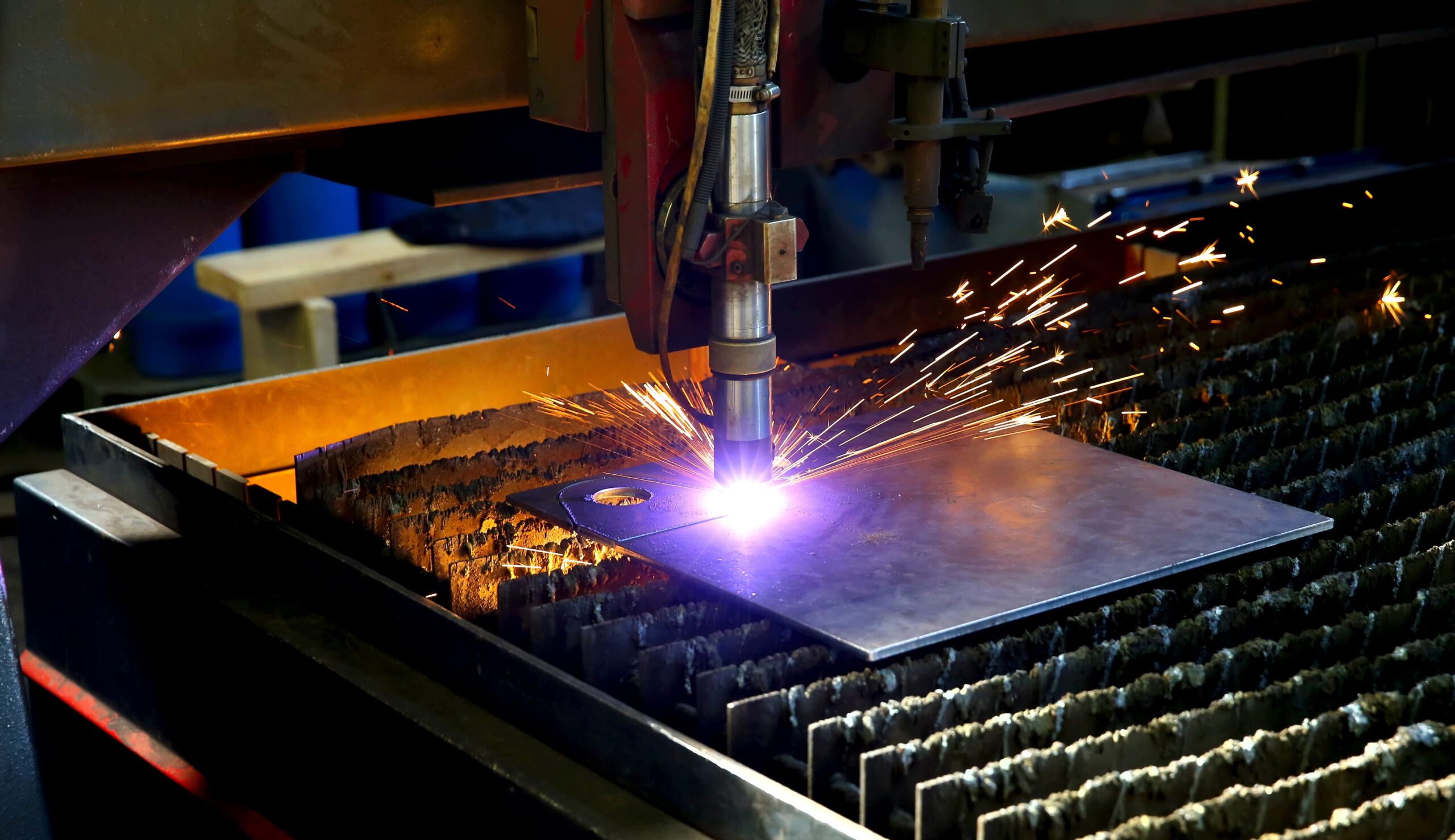 Close-up of a machine undergoing laser and plasma cutting, emphasizing the importance of a fume extractor and dust collector.