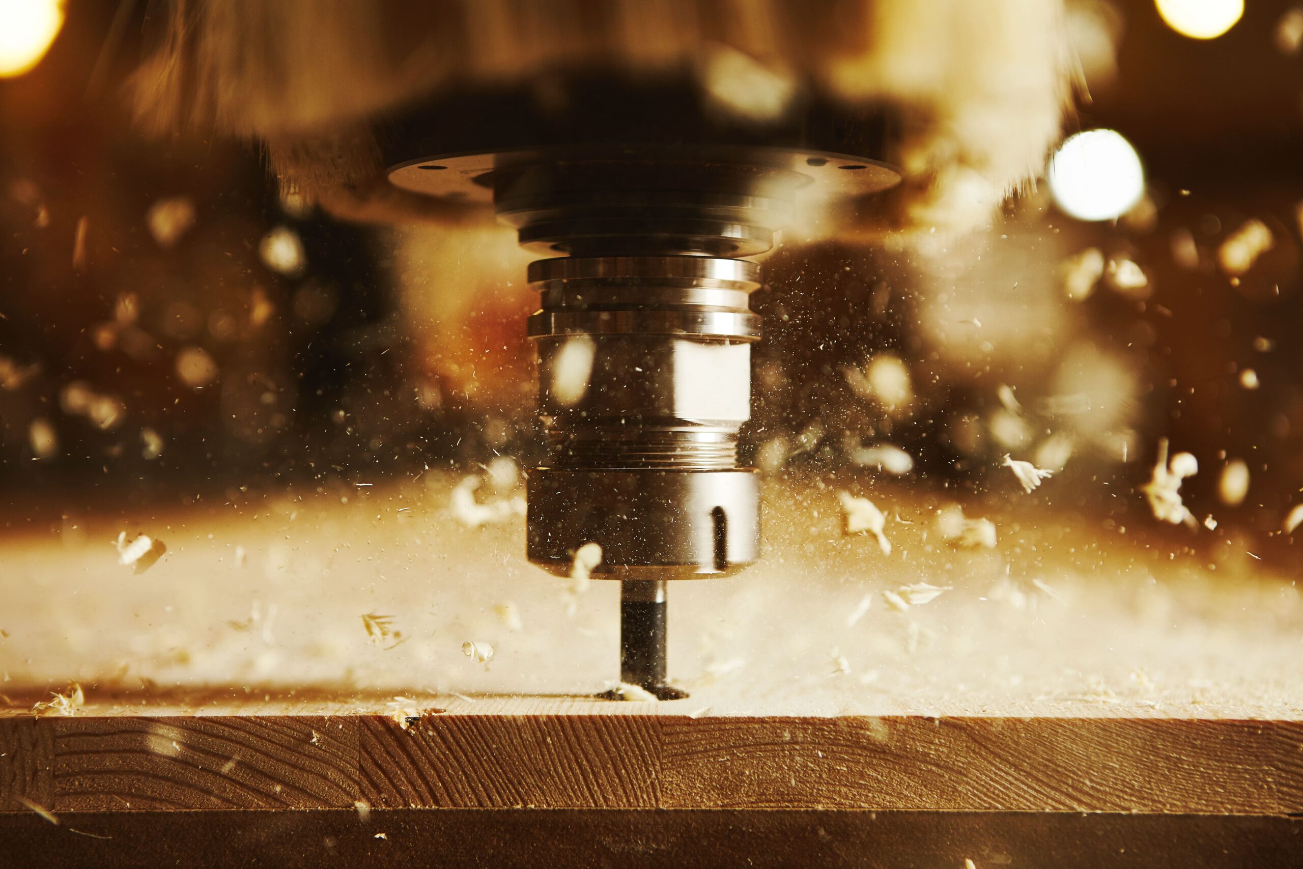 Close-up of a woodworking machine generating dust and wood particles, underscoring the importance of a dust collector.